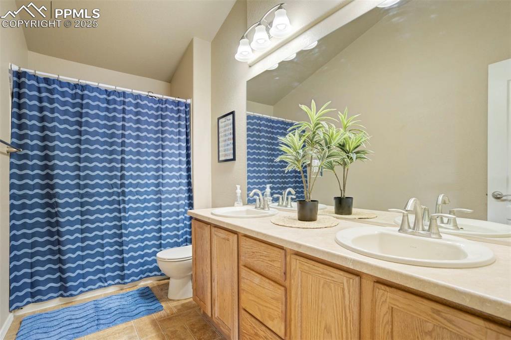 Image 38 of 50: Bathroom featuring double vanity, light tile patterned floors, and a shower