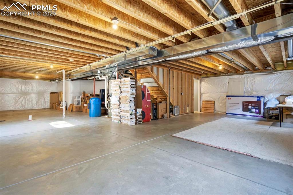 Image 40 of 50: Unfinished basement with stairway and a water pressure tank