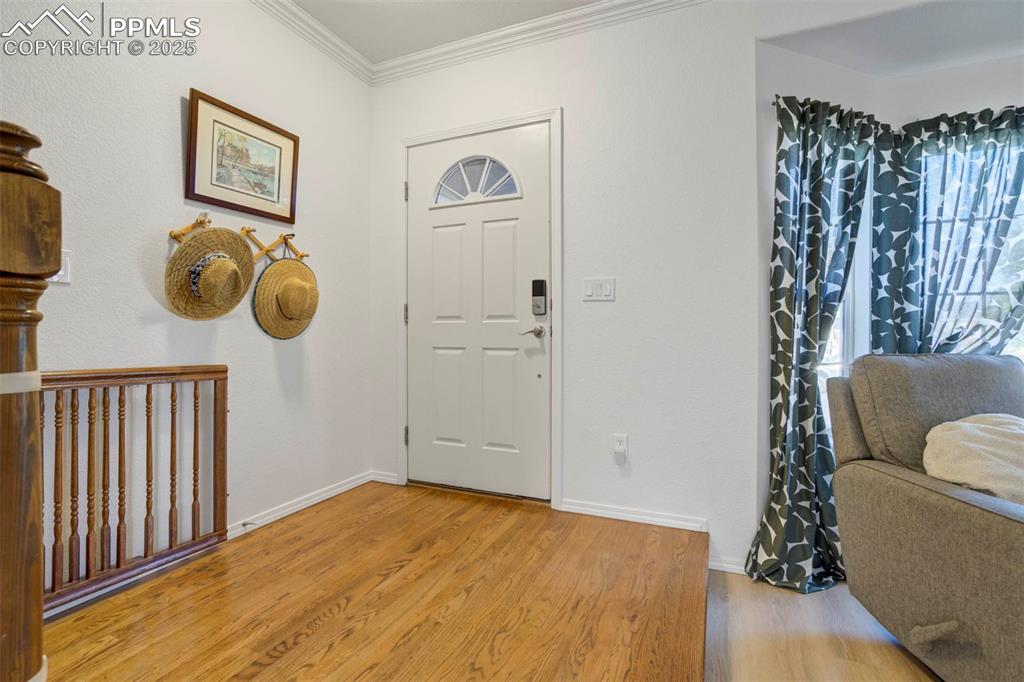 Image 5 of 50: Entryway with light wood-style floors and crown molding