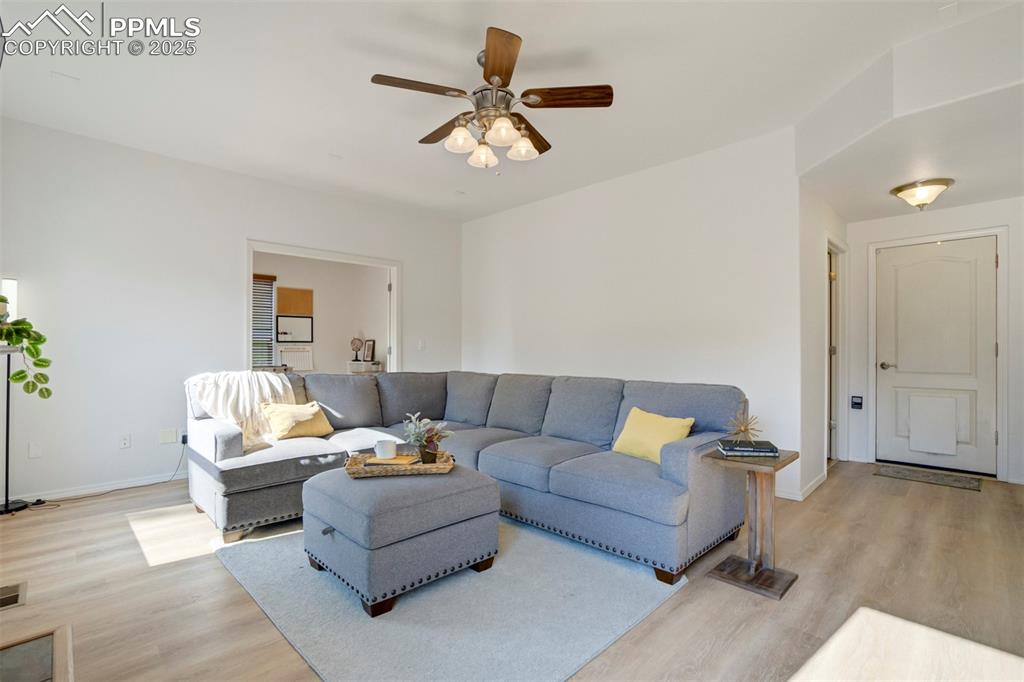 Image 7 of 50: Living area featuring light wood-type flooring and ceiling fan