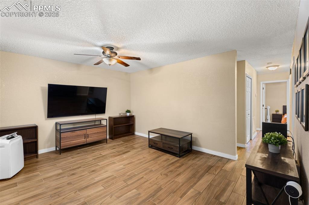 Image 8 of 23: Spacious family room with ceiling fan and media setup.