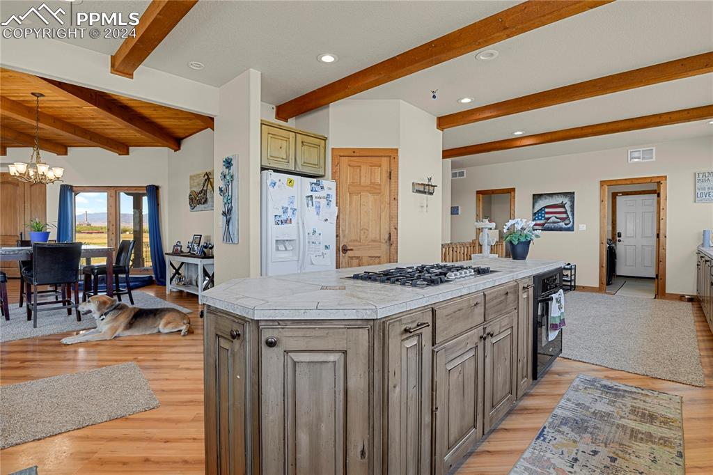 Image 23 of 45: Kitchen featuring vaulted ceiling with beams, a kitchen island, light wood-