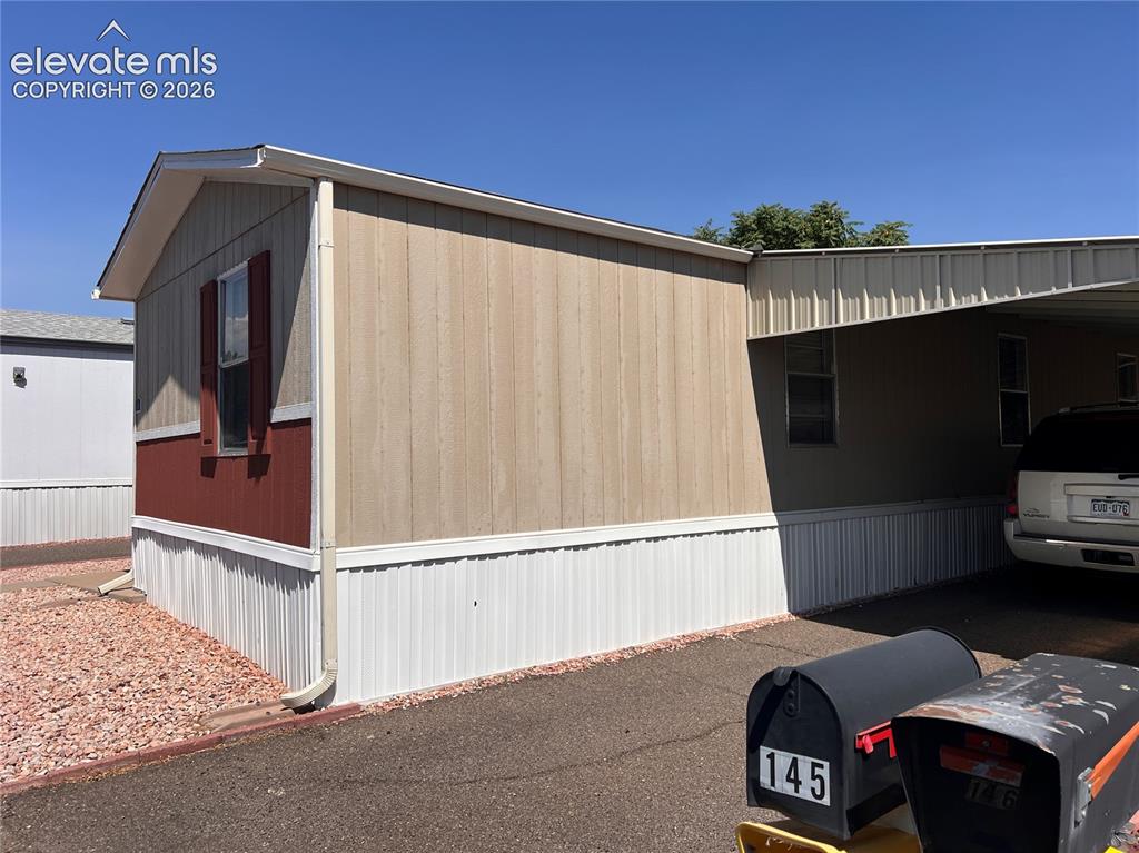 Image 13 of 16: Exterior featuring vertical panel siding, a covered carport, pitched roofli