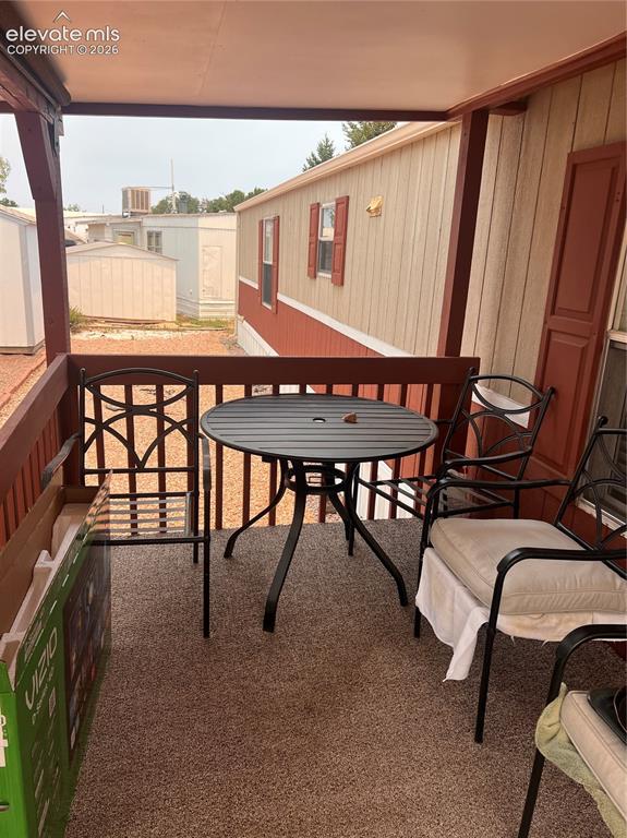 Image 14 of 16: Covered porch with wood railing and granular-finish flooring