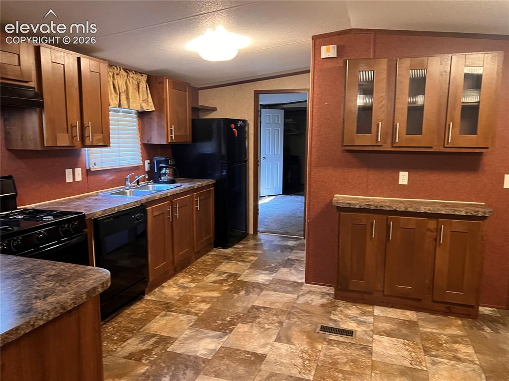Image 4 of 24: Kitchen featuring wood-finish cabinetry, patterned flooring, and a stainles