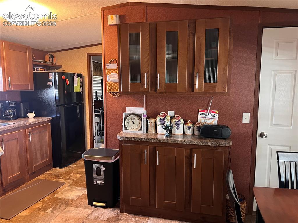 Image 5 of 16: Kitchen featuring wood-finish cabinetry, patterned countertops, and pattern