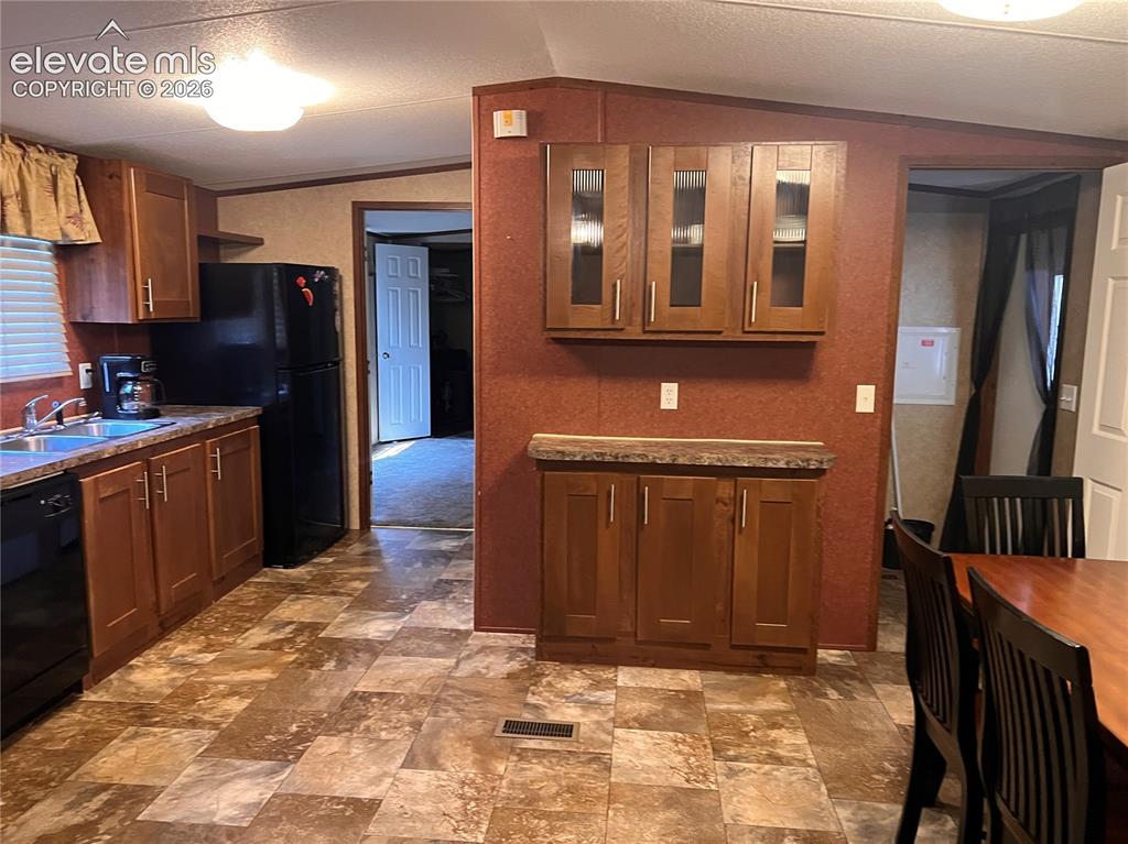 Image 5 of 24: Kitchen featuring wood-finish cabinetry, stainless steel sink, black refrig