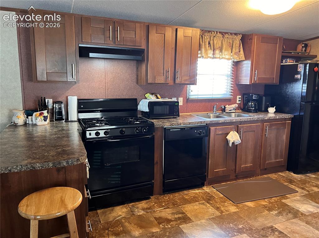 Image 6 of 16: Full kitchen featuring wood-finish cabinetry, black appliances including a