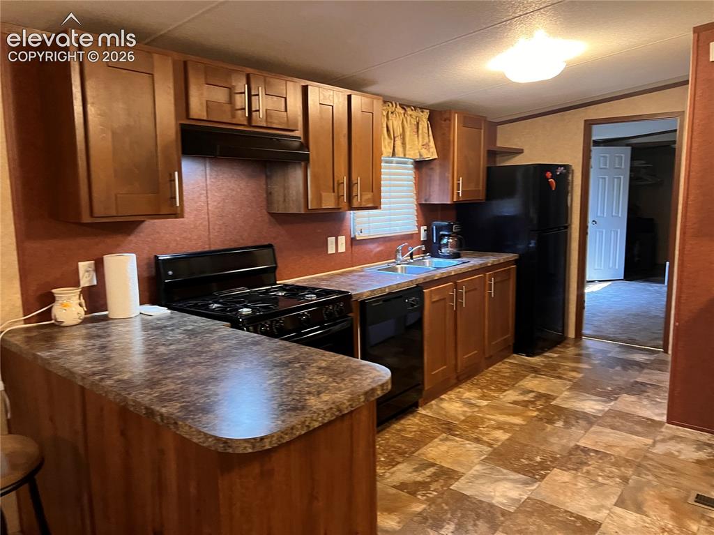 Image 6 of 24: Kitchen featuring wood-finish cabinetry, black appliances, a double basin s