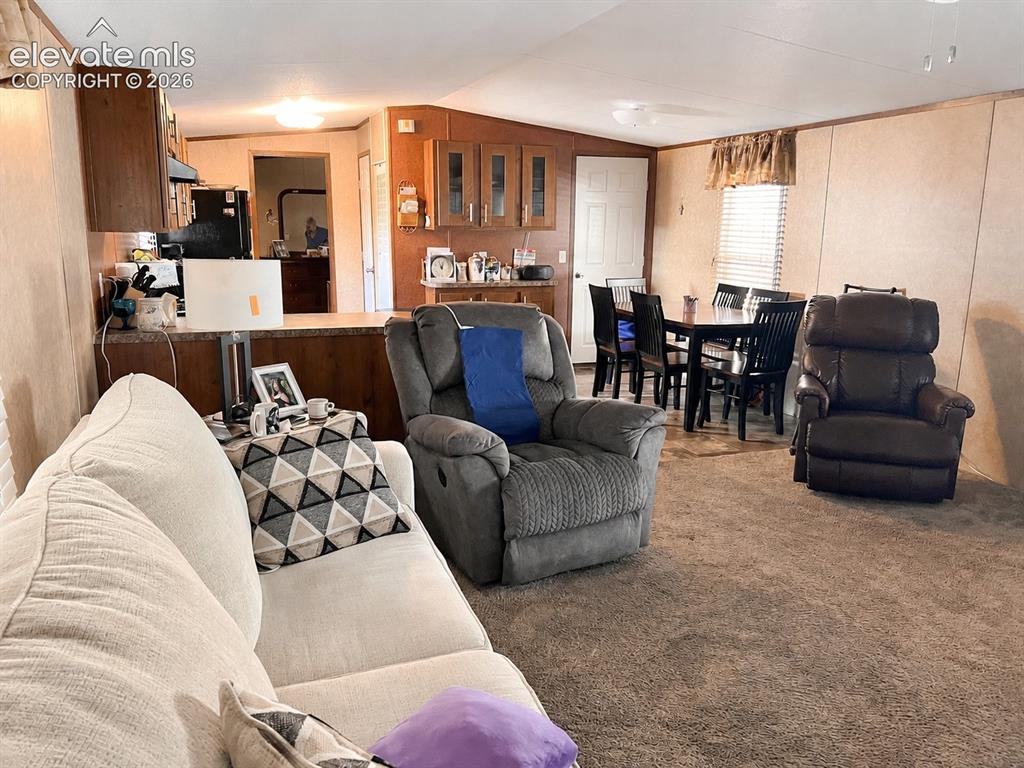 Image 9 of 16: Open-concept living area with a kitchen peninsula, wood-finish cabinetry, b
