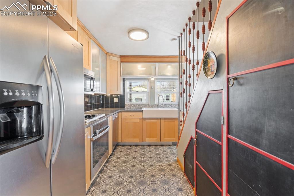 Image 12 of 37: Kitchen with stainless steel appliances, light brown cabinets, decorative b