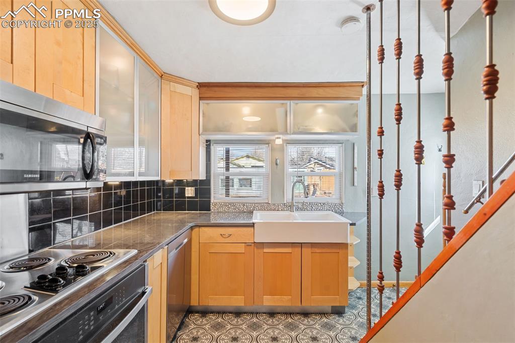 Image 13 of 37: Kitchen featuring stainless steel appliances, backsplash, glass insert cabi