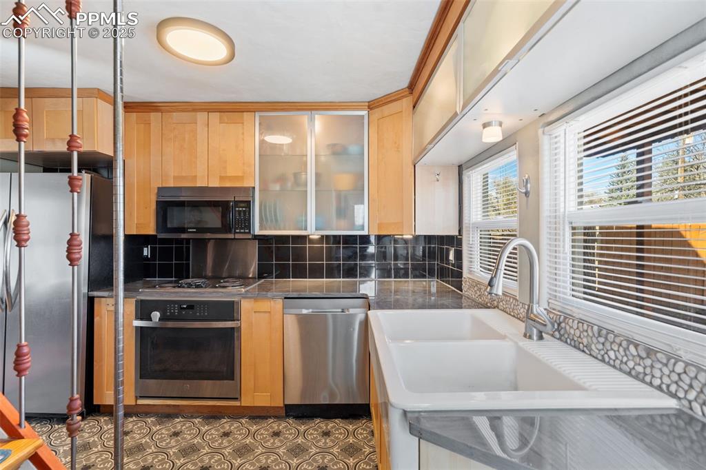 Image 14 of 37: Kitchen with appliances with stainless steel finishes, decorative backsplas