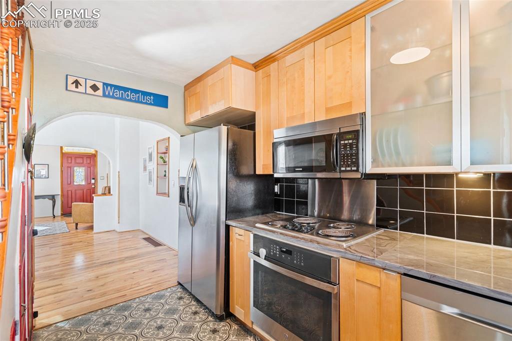 Image 15 of 37: Kitchen with stainless steel appliances, backsplash, light brown cabinetry,