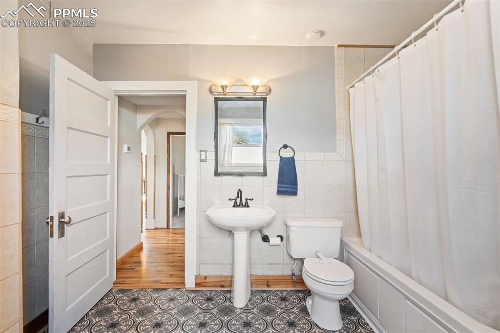 Image 20 of 37: Bathroom featuring tile walls, shower / bath combo, and tile patterned floo