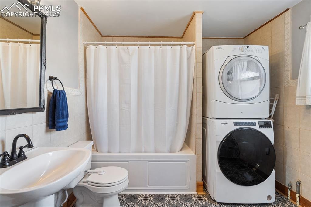 Image 21 of 37: Full bathroom with tile walls, shower / bath combo with shower curtain, cro