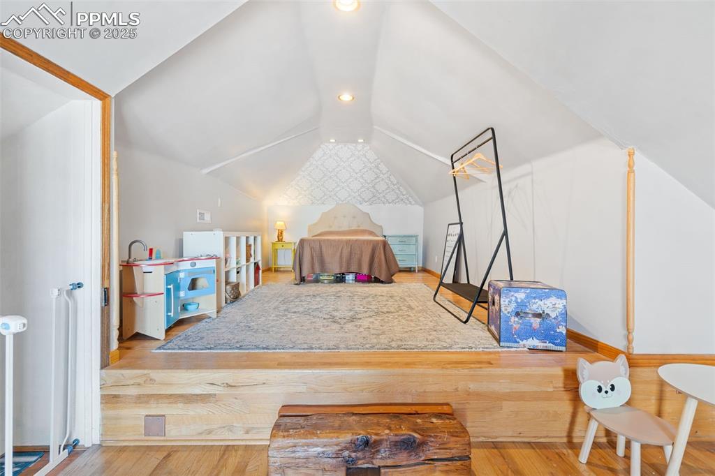 Image 22 of 37: Bedroom featuring vaulted ceiling, wood finished floors, and recessed light