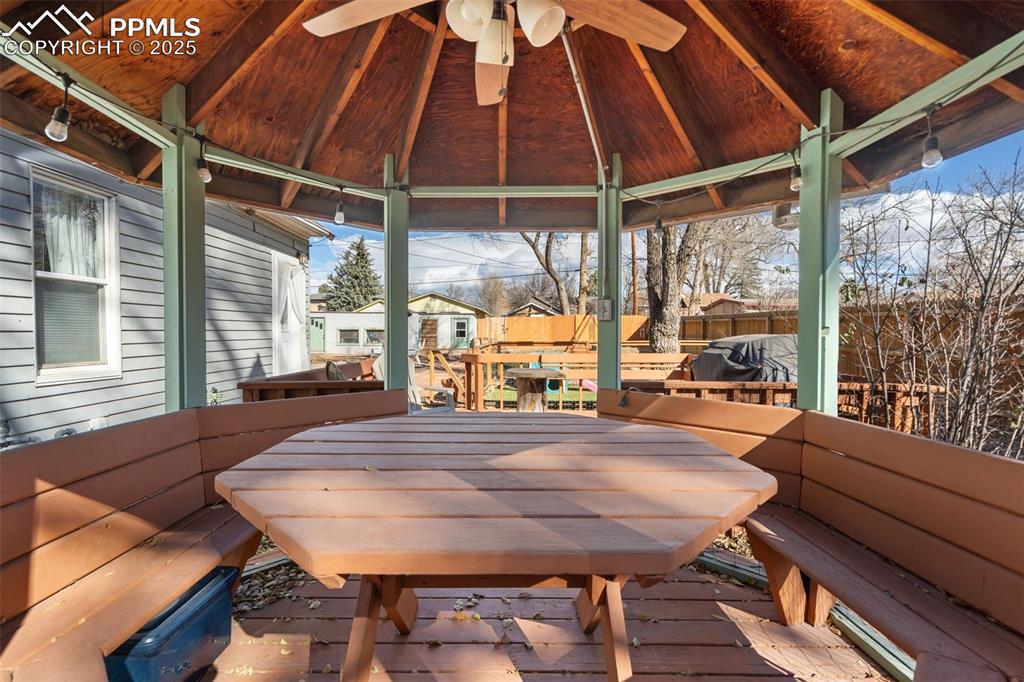 Image 27 of 37: Wooden terrace featuring outdoor dining area, a gazebo, and an outbuilding