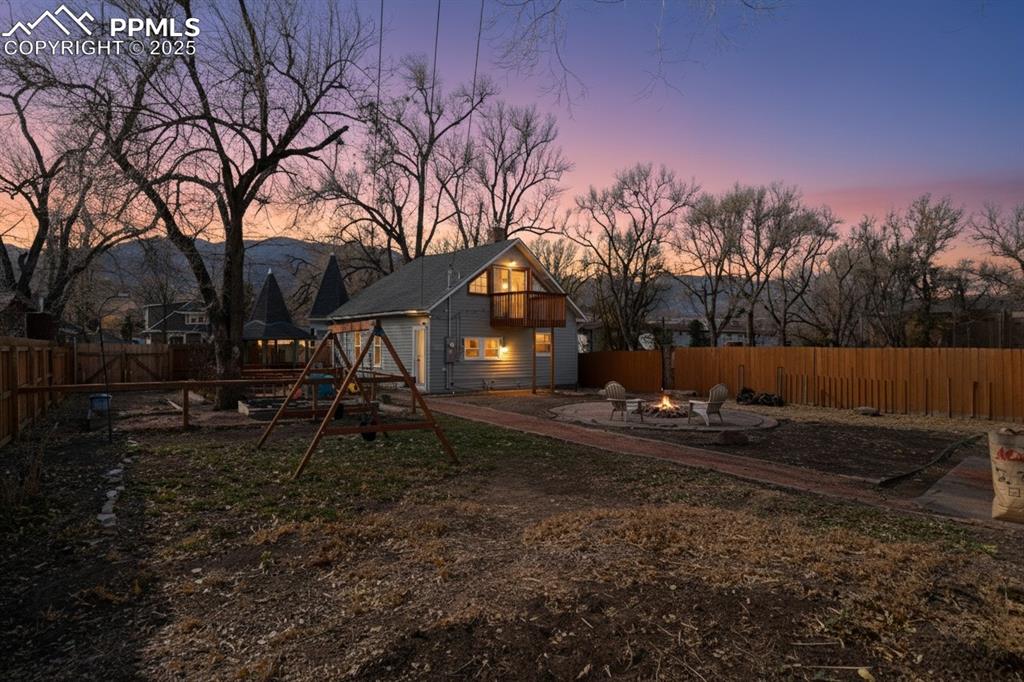 Image 4 of 37: Yard at dusk featuring a fenced backyard, a fire pit, a playground, and a p