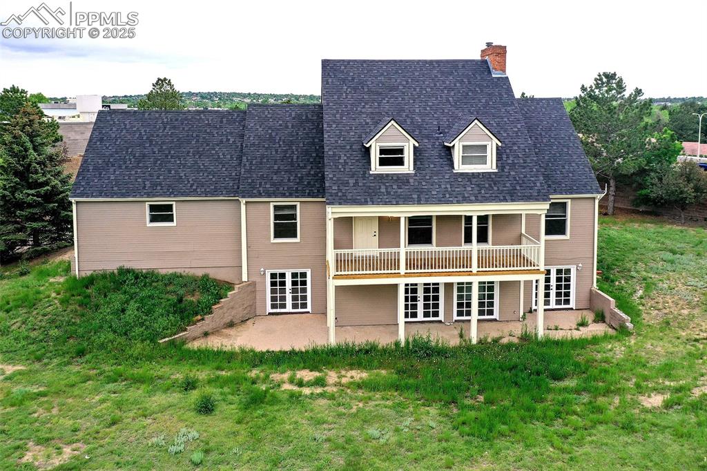 Caption: Back of property featuring a patio area, a chimney, french doors, and roof with shingles