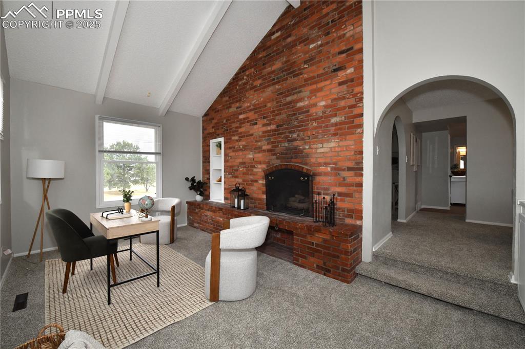 Image 10 of 36: Living area with high vaulted ceiling, carpet floors, a brick fireplace, be