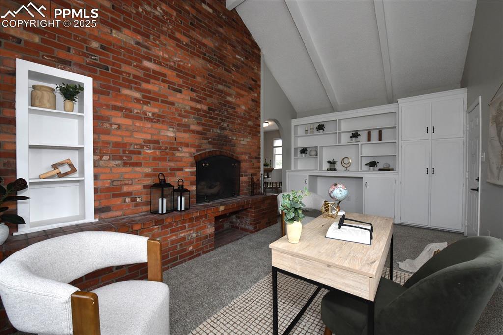 Image 11 of 36: Living room with built in features, carpet flooring, beamed ceiling, a fire
