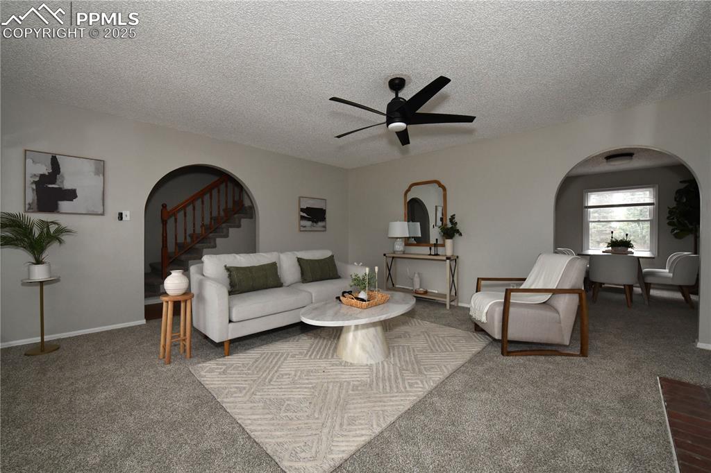 Image 2 of 36: Carpeted living room featuring arched walkways, a textured ceiling, and a c