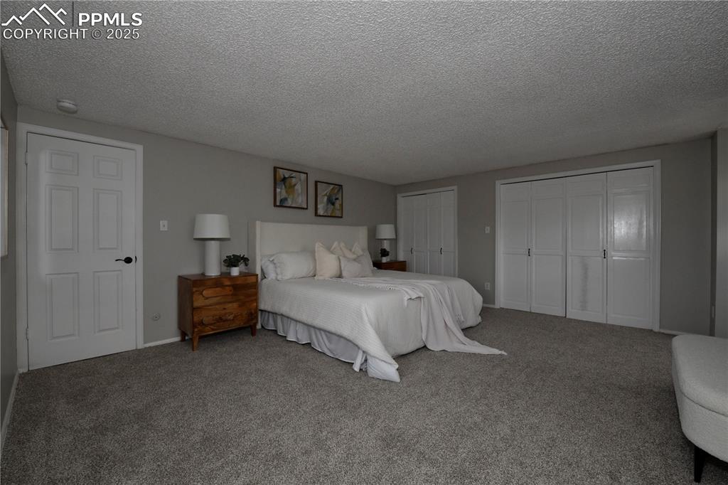 Image 20 of 36: Carpeted bedroom featuring a textured ceiling and multiple closets