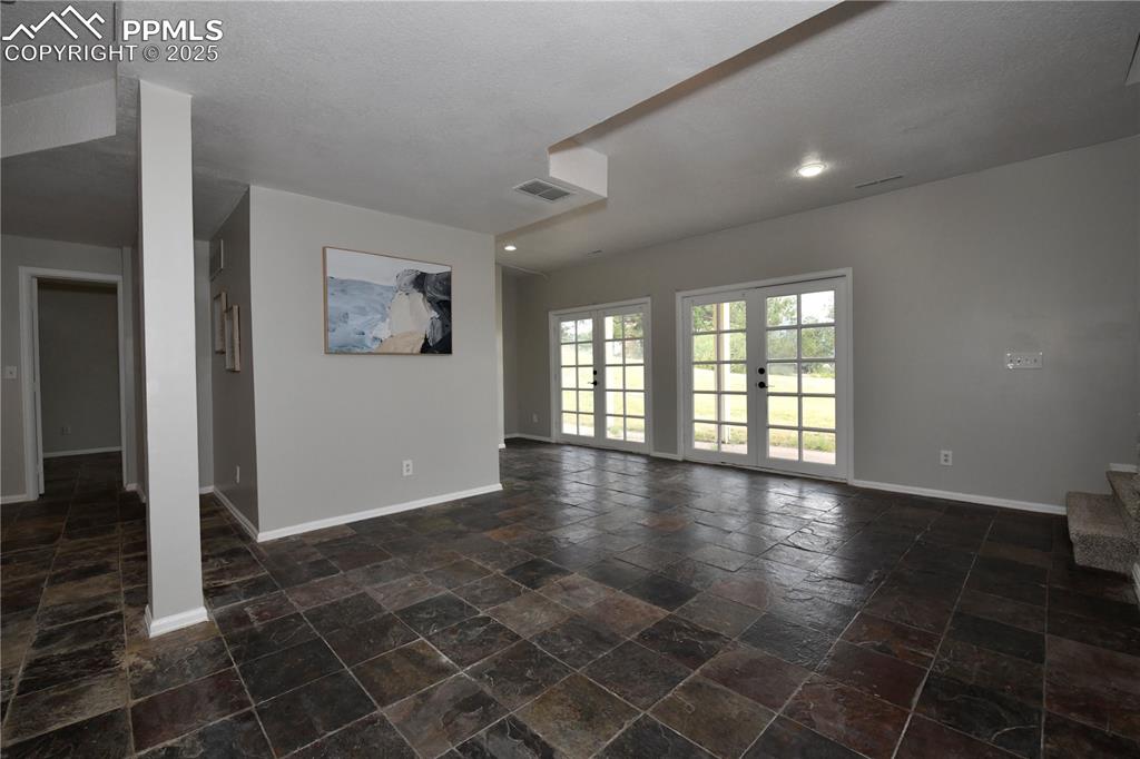 Image 22 of 36: Unfurnished living room featuring baseboards and stone tile floors