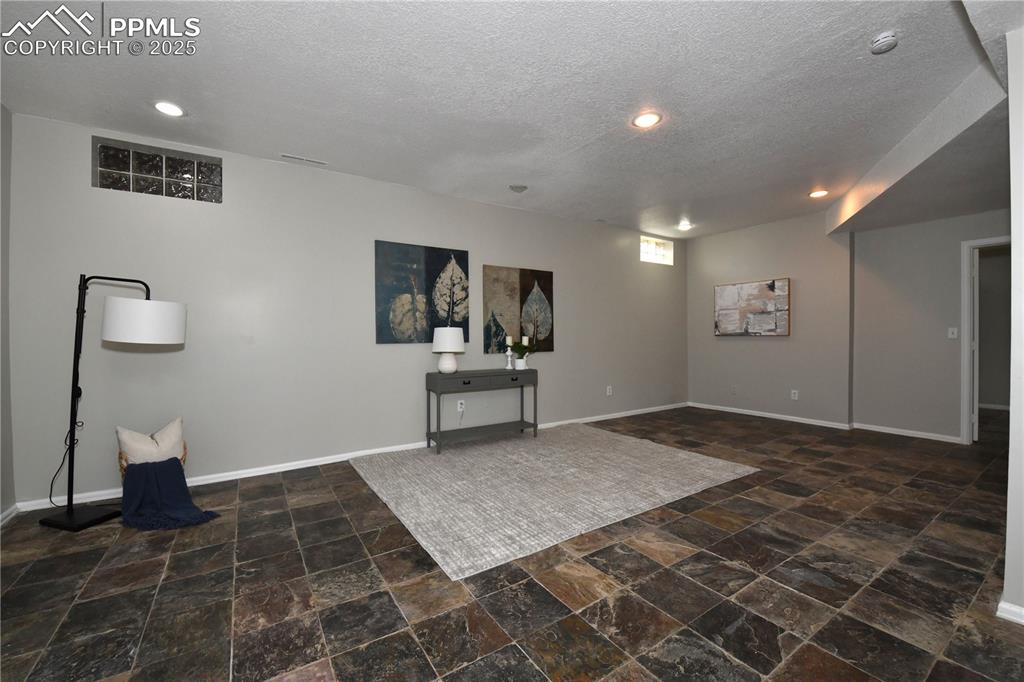 Image 23 of 36: Basement with stone finish flooring, a textured ceiling, and recessed light