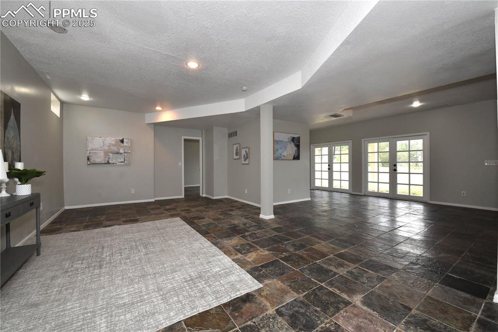 Image 24 of 36: Spare room with stone finish flooring, a textured ceiling, and recessed lig