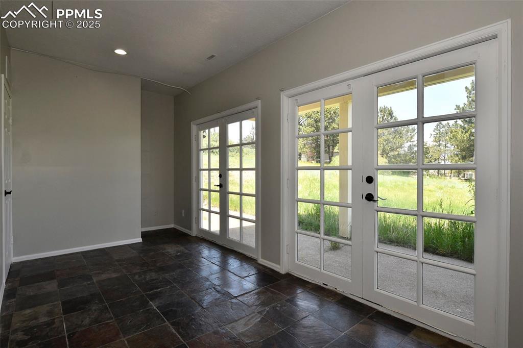 Image 26 of 36: Doorway with baseboards, plenty of natural light, stone tile floors, french