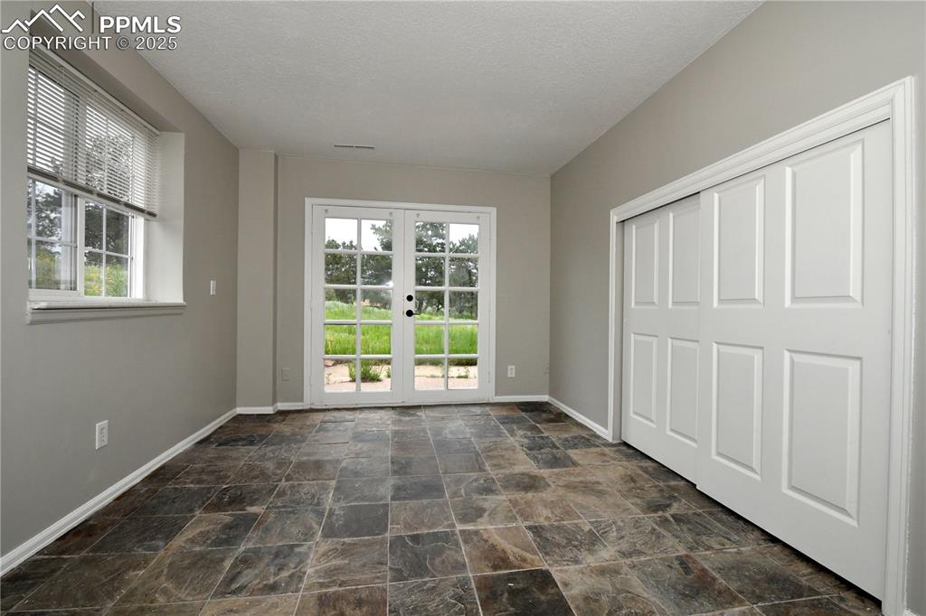 Image 27 of 36: Unfurnished bedroom featuring baseboards, dark stone finish flooring, frenc