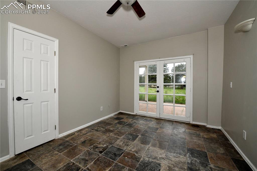 Image 28 of 36: Unfurnished room featuring french doors, stone tile floors, ceiling fan, an