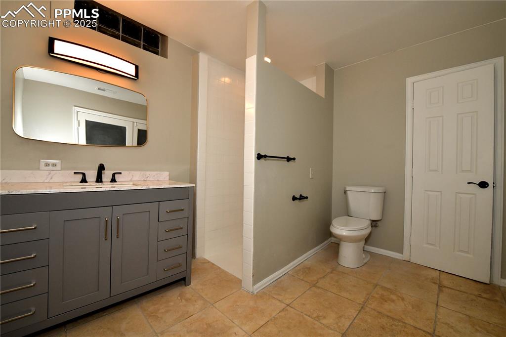 Image 29 of 36: Bathroom featuring vanity, toilet, tile patterned flooring, and tiled showe