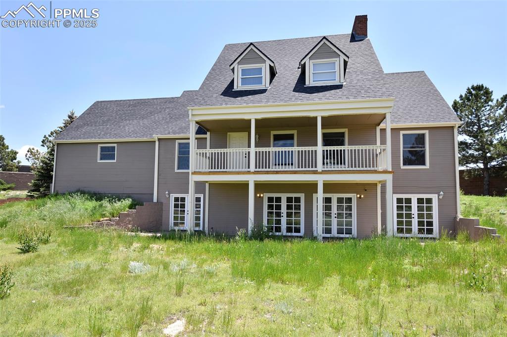 Image 31 of 36: Back of house with french doors, a chimney, roof with shingles, a balcony,