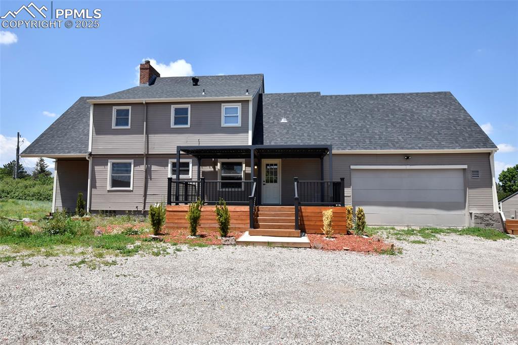 Image 32 of 36: View of front of home featuring a chimney, an attached garage, driveway, ro