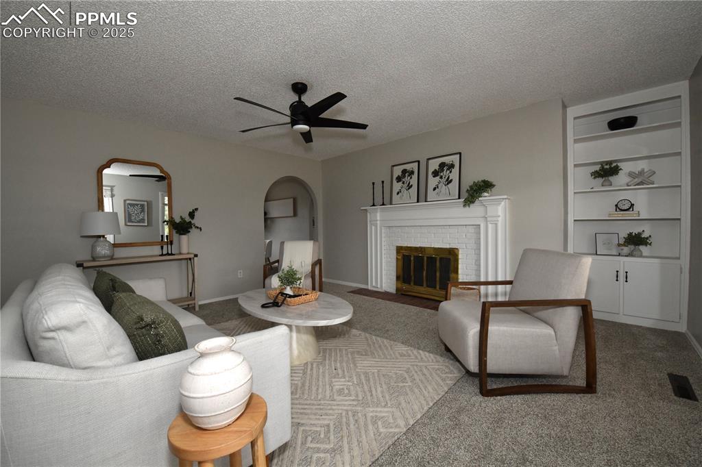 Image 4 of 36: Carpeted living room with arched walkways, a textured ceiling, a ceiling fa