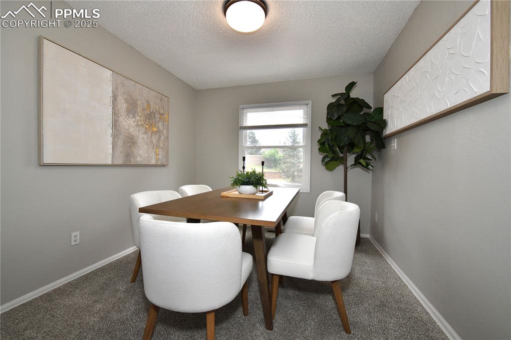 Image 7 of 36: Carpeted dining space with a textured ceiling and baseboards