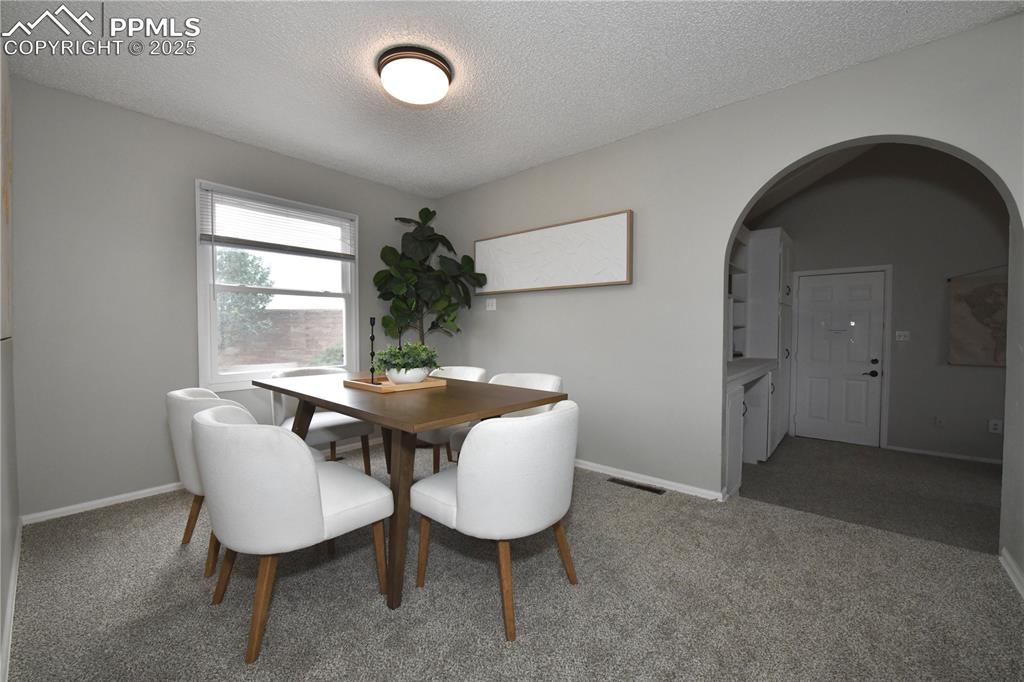 Image 8 of 36: Carpeted dining area featuring a textured ceiling and arched walkways