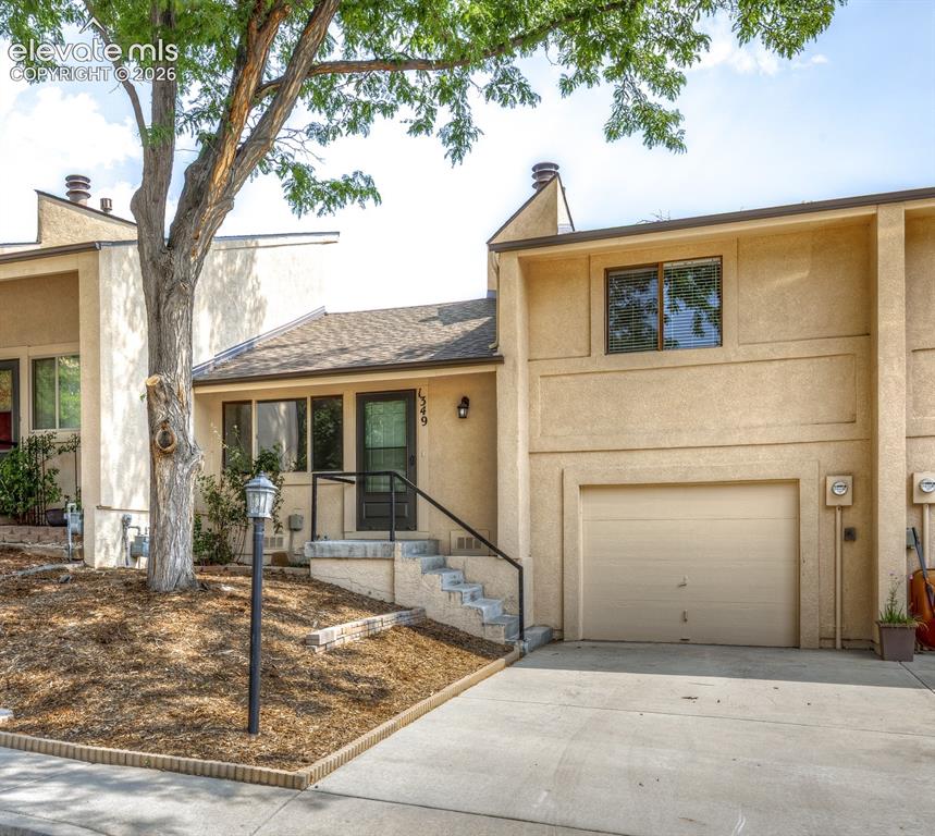 Caption: Stucco exterior with an attached garage, paved driveway, and covered entry