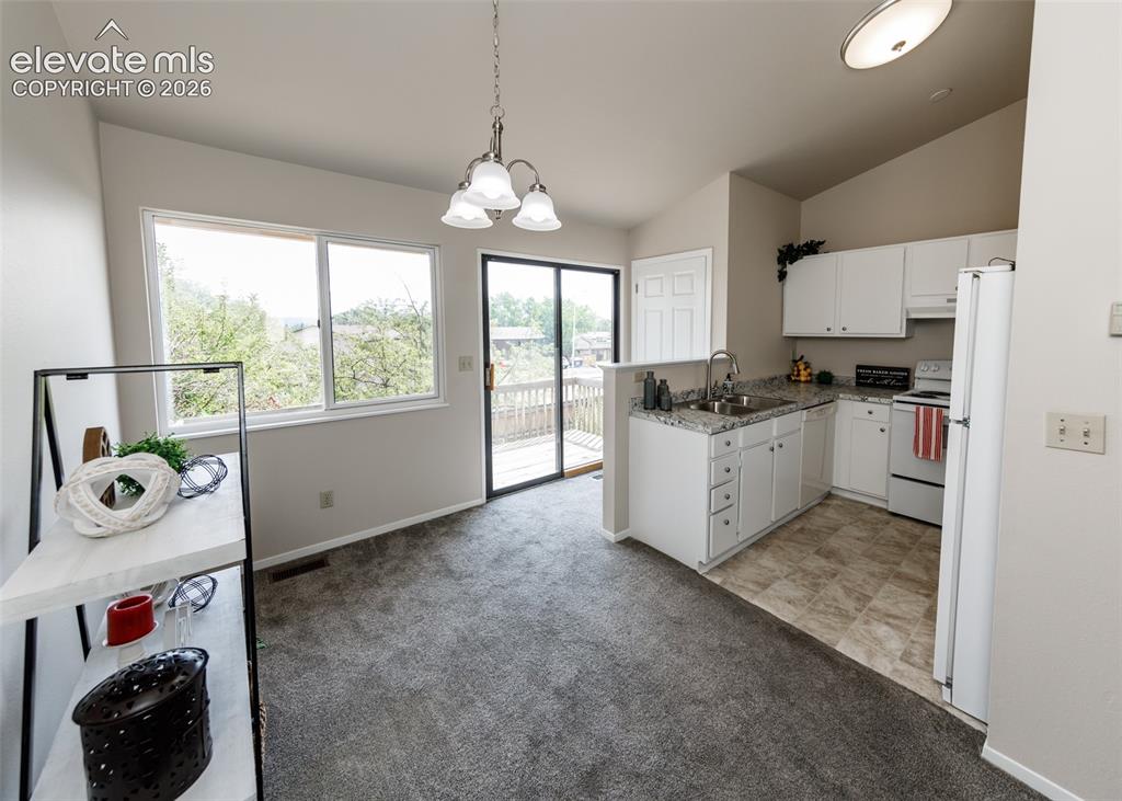 Image 12 of 36: Kitchen and dining area featuring white cabinetry, light-toned countertops,