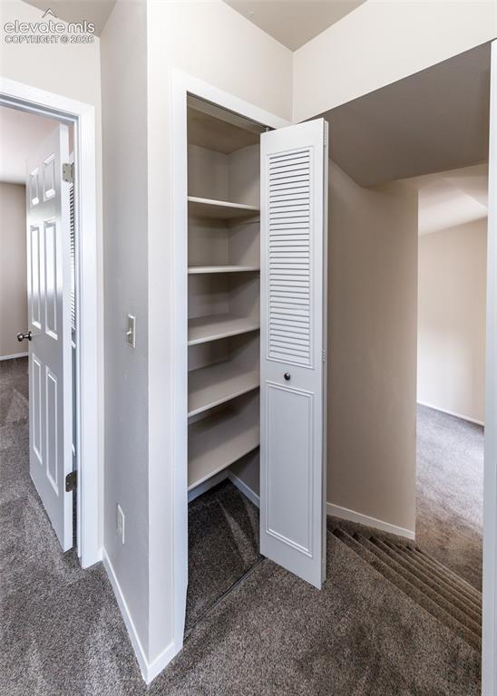 Image 22 of 36: Built-in shelving with a louvered bifold door, painted white trim, and ligh