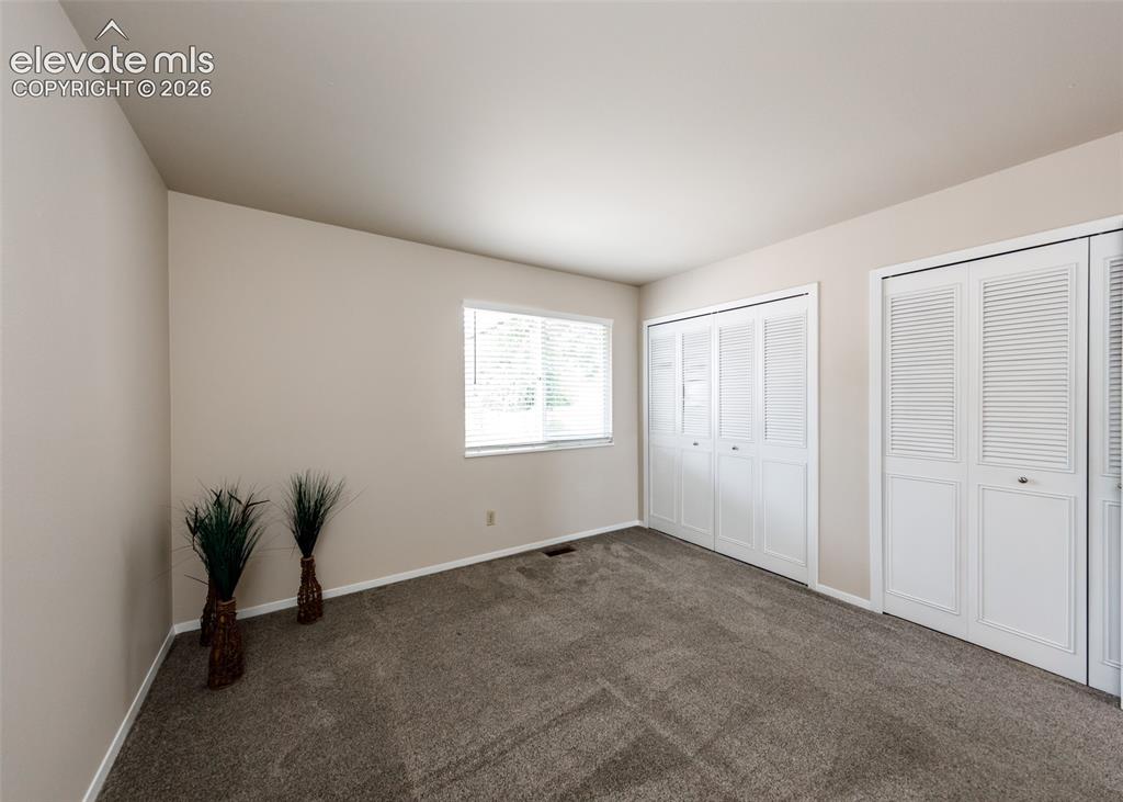 Image 23 of 36: Carpeted room featuring a white-trimmed window with blinds and two sets of