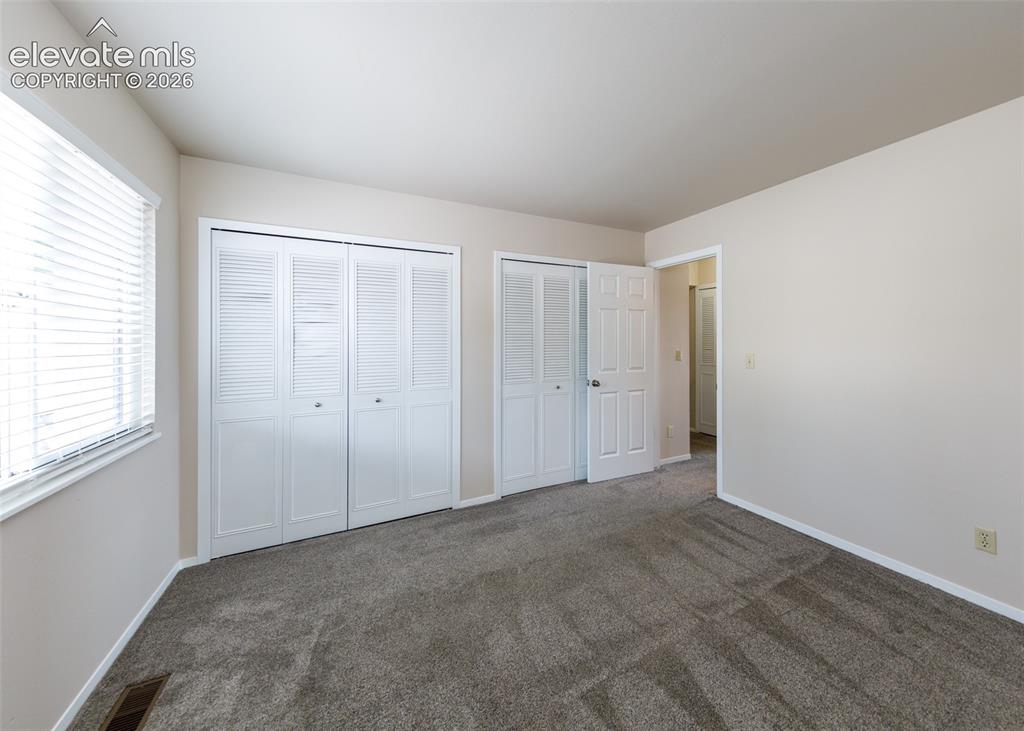 Image 24 of 36: Neutral wall paint, window with blinds, carpeted flooring, and white bi-fol