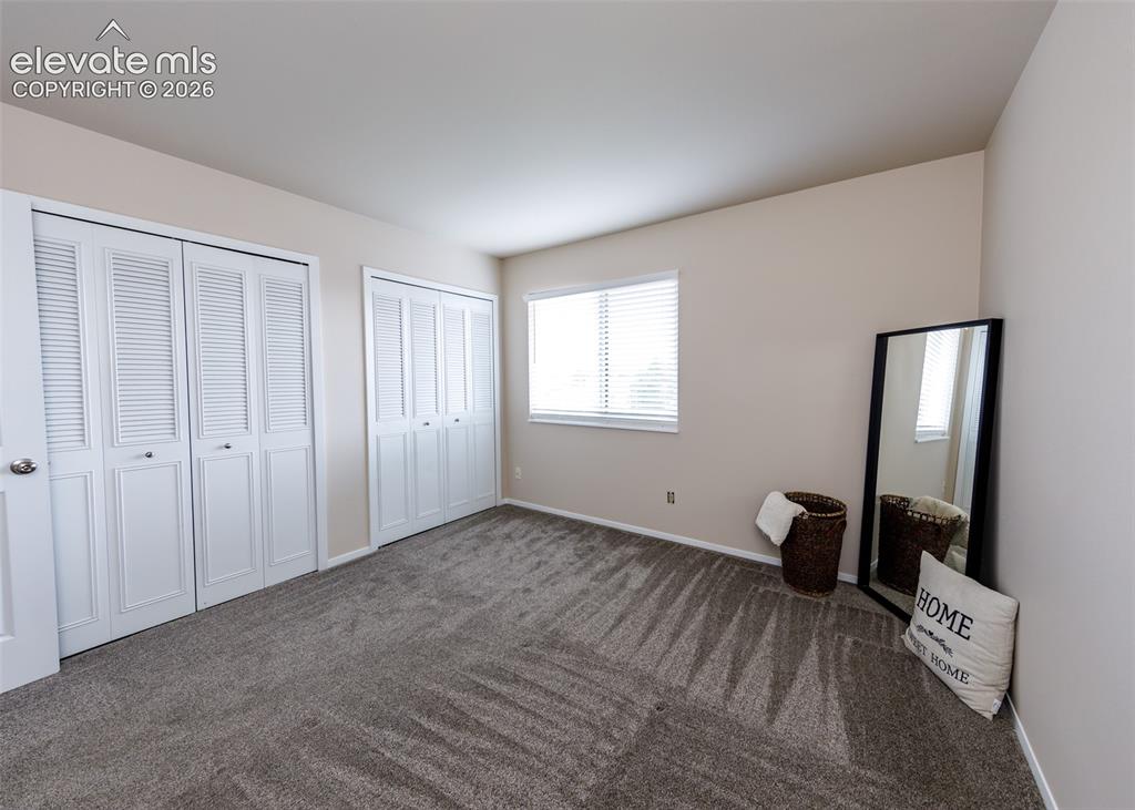 Image 28 of 36: Neutral wall paint, two sets of louvered bi-fold closet doors, wall-to-wall