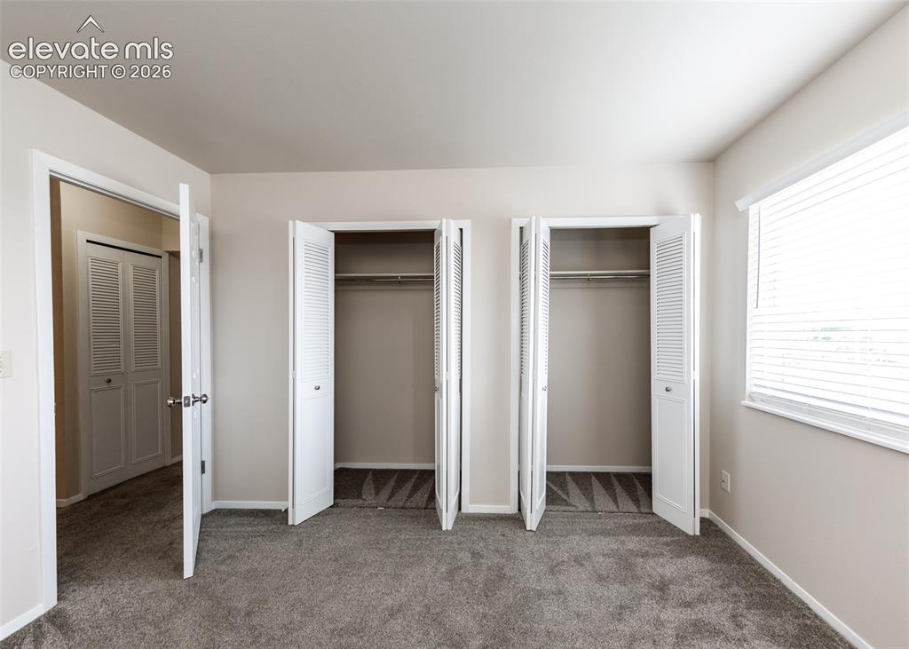 Image 29 of 36: Plush carpeting with neutral wall tones, two bi-fold louvered closets, and