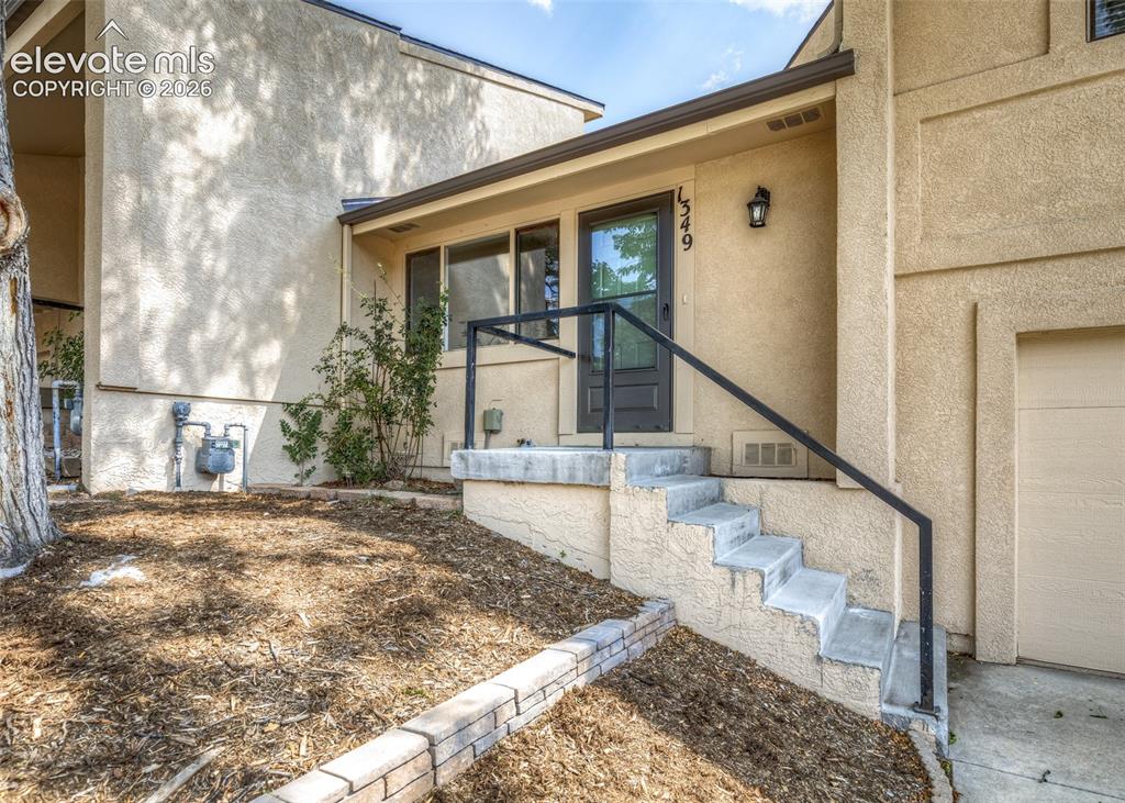 Image 3 of 36: Stucco exterior with concrete steps and an integrated black metal handrail