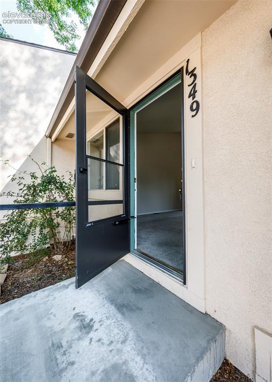 Image 4 of 36: Stucco exterior with a concrete entry and a black screen door
