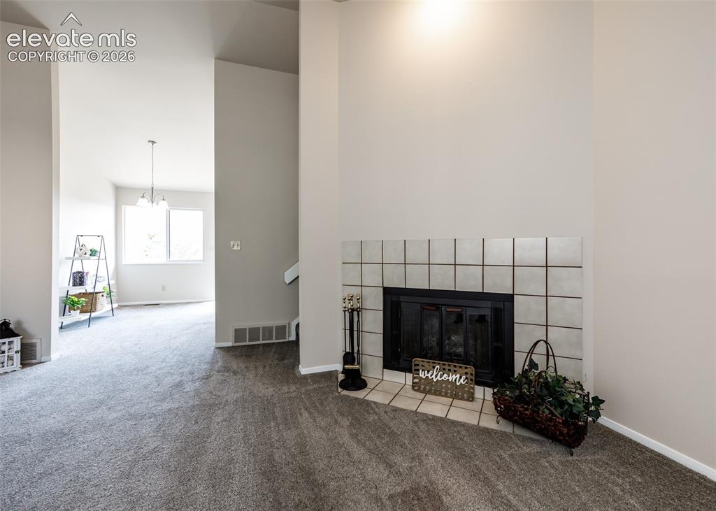 Image 7 of 36: Carpeted flooring throughout, with an integrated fireplace featuring a tile